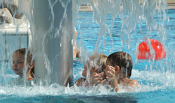 Kinder im Schwimmbecken unter einem Wasserpilz